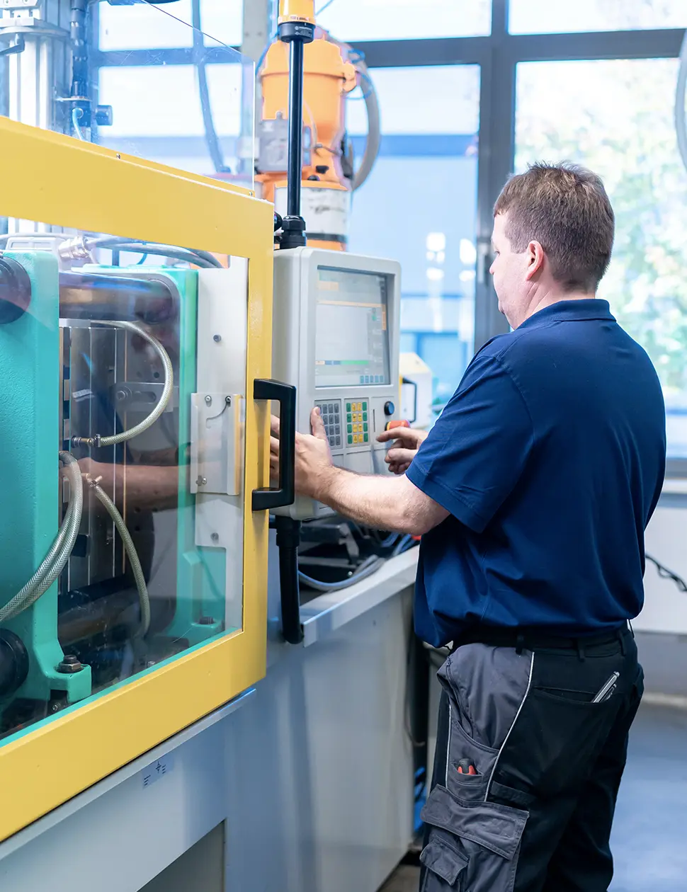 Mitarbeiter bedient eine Spritzgußmaschine